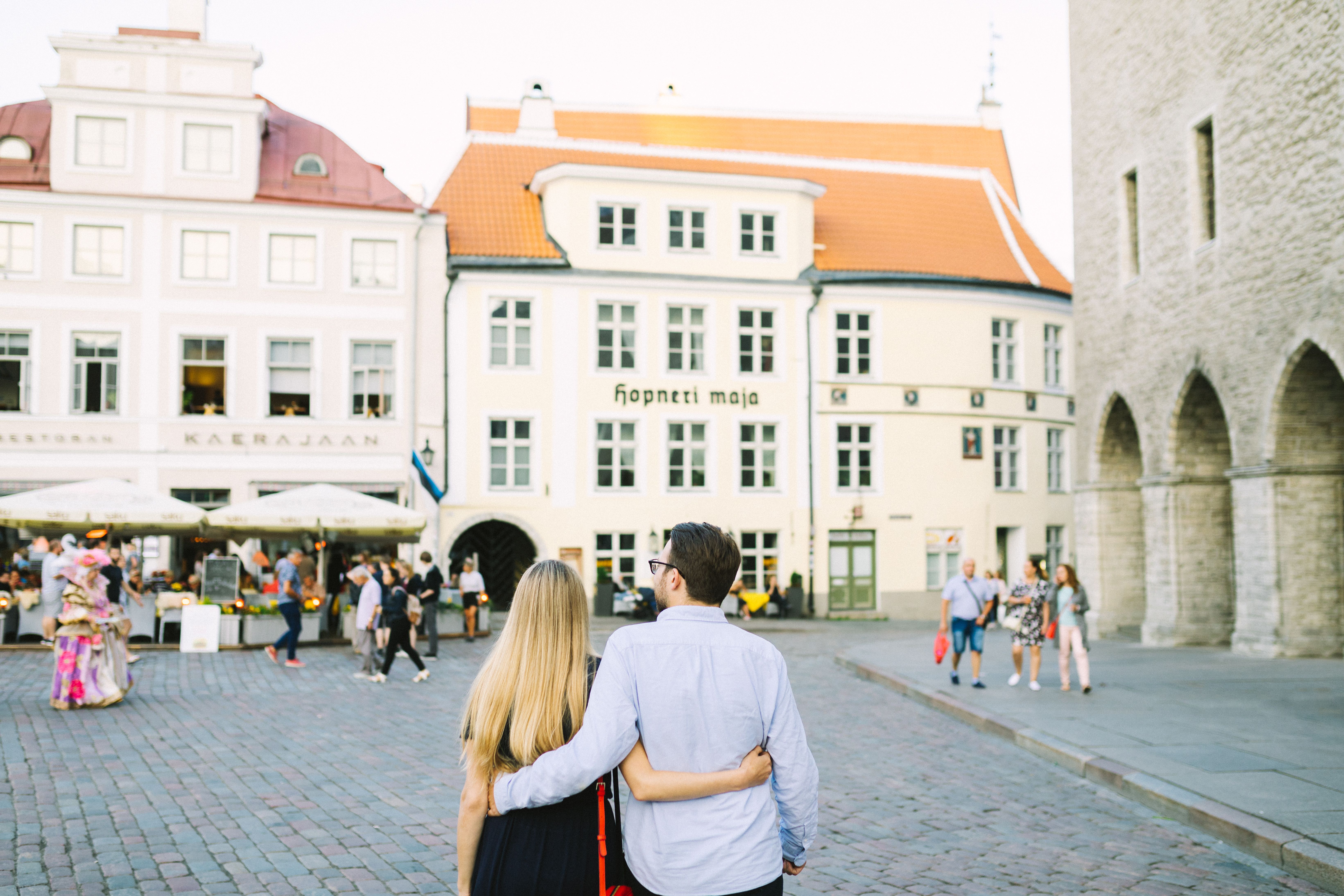 Man and woman holding around each other while walking in the Town Hall Square in Tallinn, Estonia.