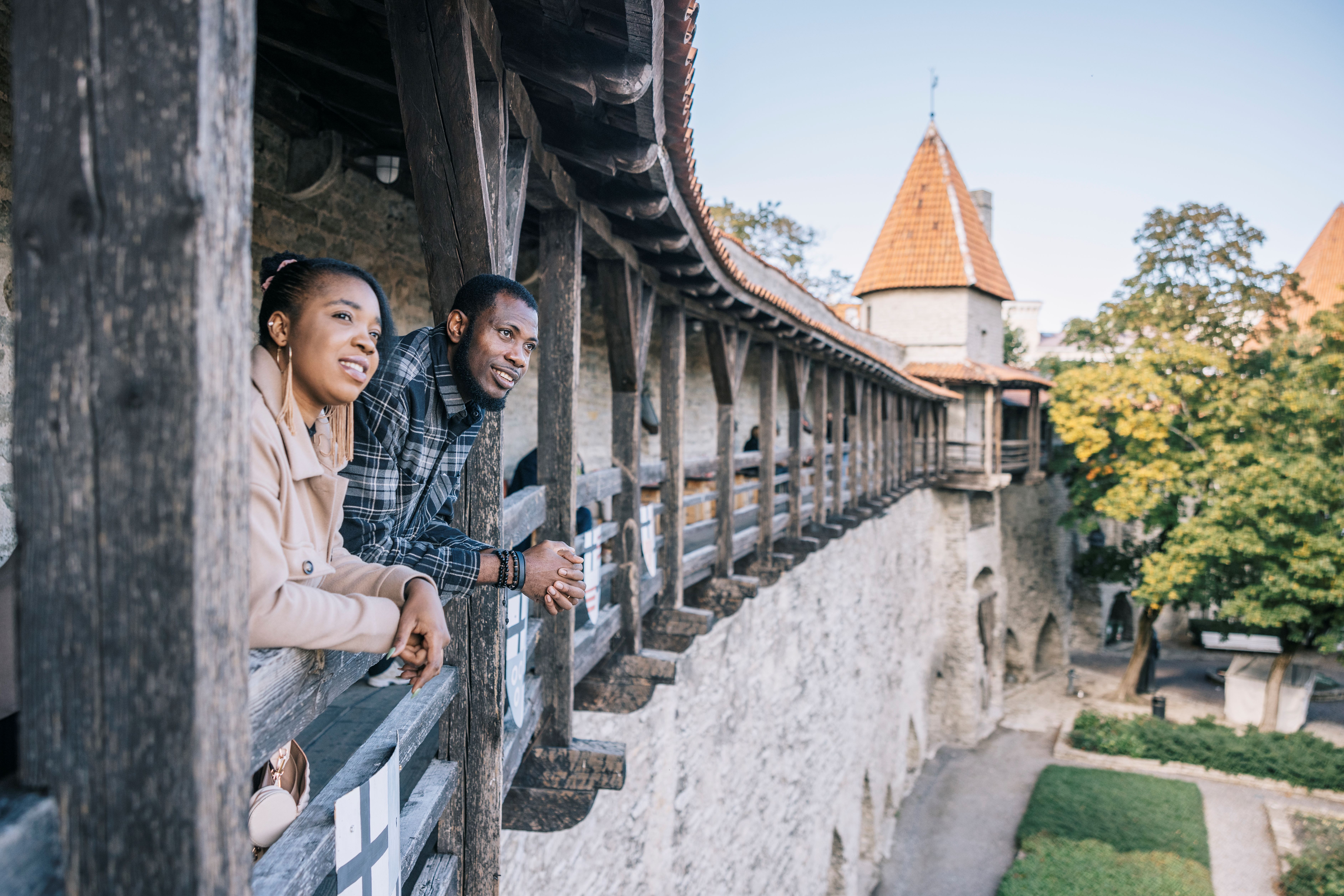 
Mies ja nainen nojaavat keskiaikaiseen muuriin ja katselevat Tallinnan vanhaakaupunkia.