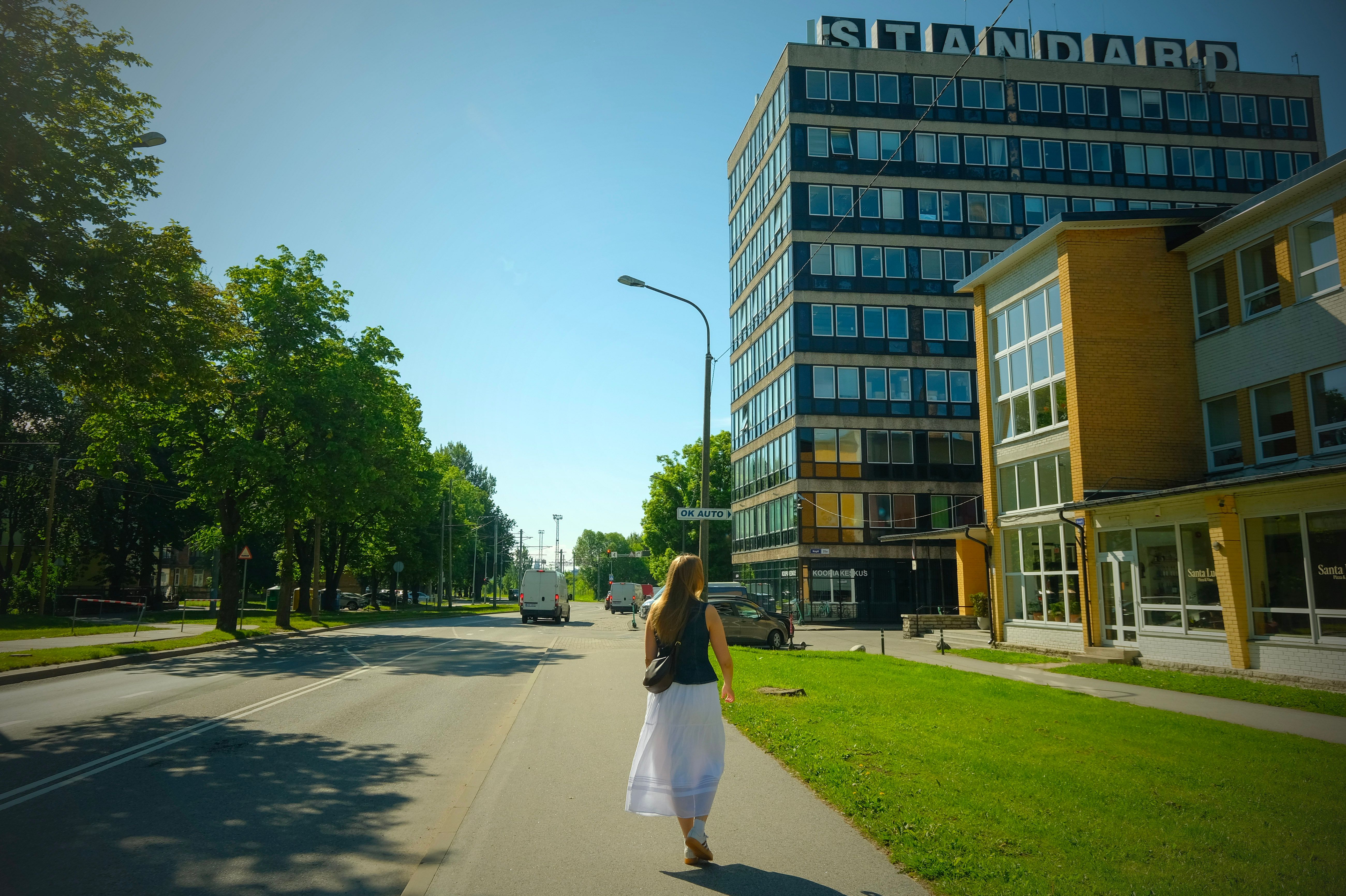 Jalak&auml;ija liigub Tallinna Pelgulinna Standardi hoone k&otilde;rval p&auml;ikeselisel linnat&auml;naval roheluse keskel.