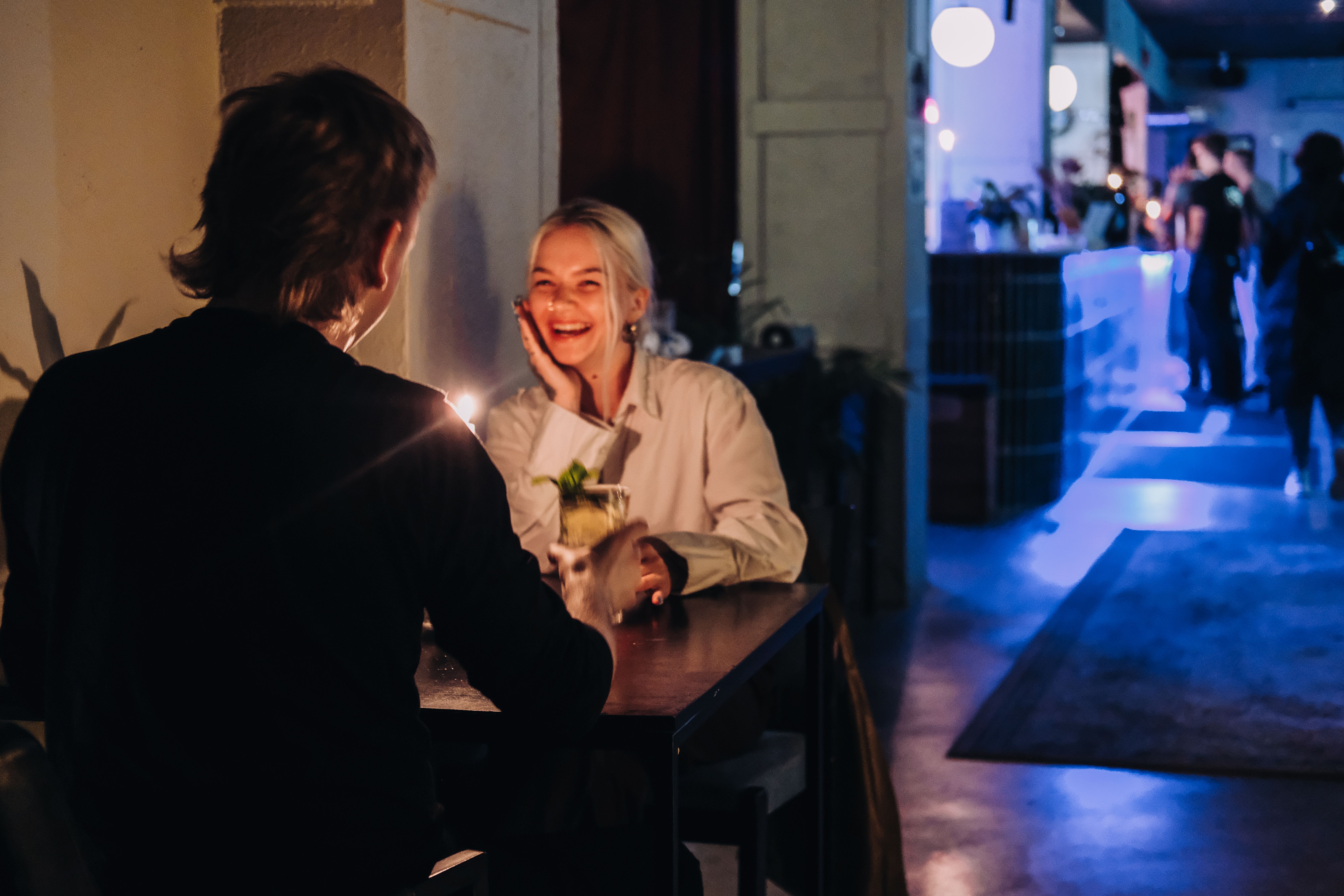 Kaksi ihmist&auml; keskustelee kynttil&auml;nvalossa p&ouml;yd&auml;n &auml;&auml;ress&auml; SUHE-baarissa Tallinnassa, tunnelmallinen ilta ja cocktailit.
