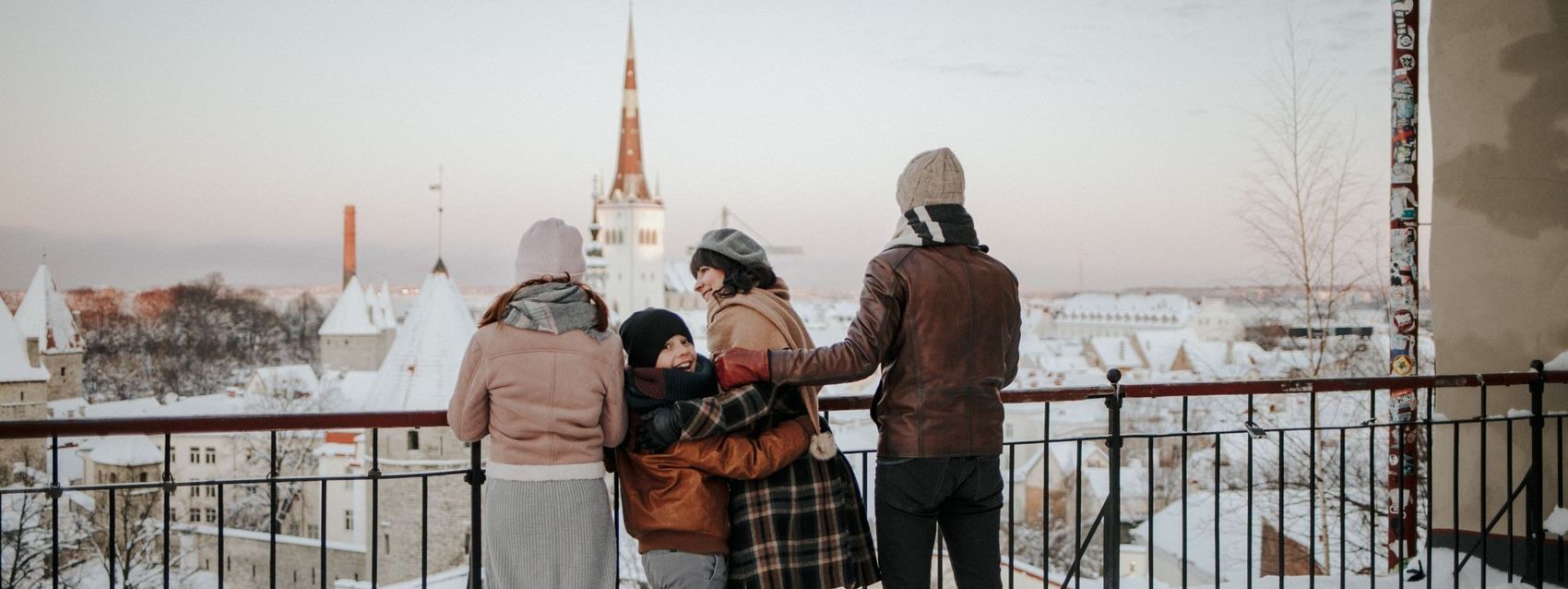 Семья смотрит на город со смотровой площадки Паткули на Вышгороде зимой. Впереди виден шпиль церкви Олевисте, Старый город, Таллинн, Эстония