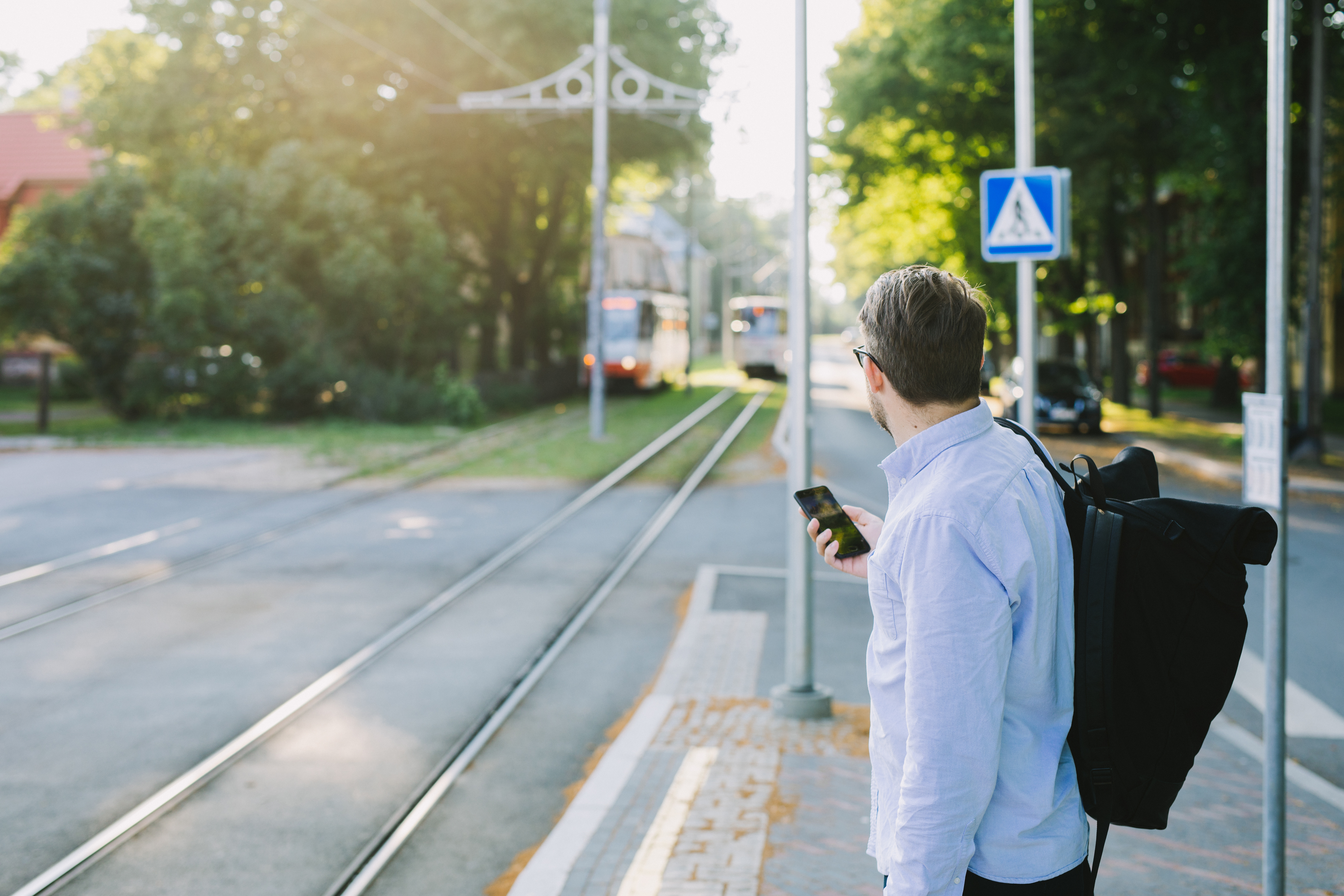 Seljakoti ja mobiiltelefoniga mees Tallinnas transporti ootamas