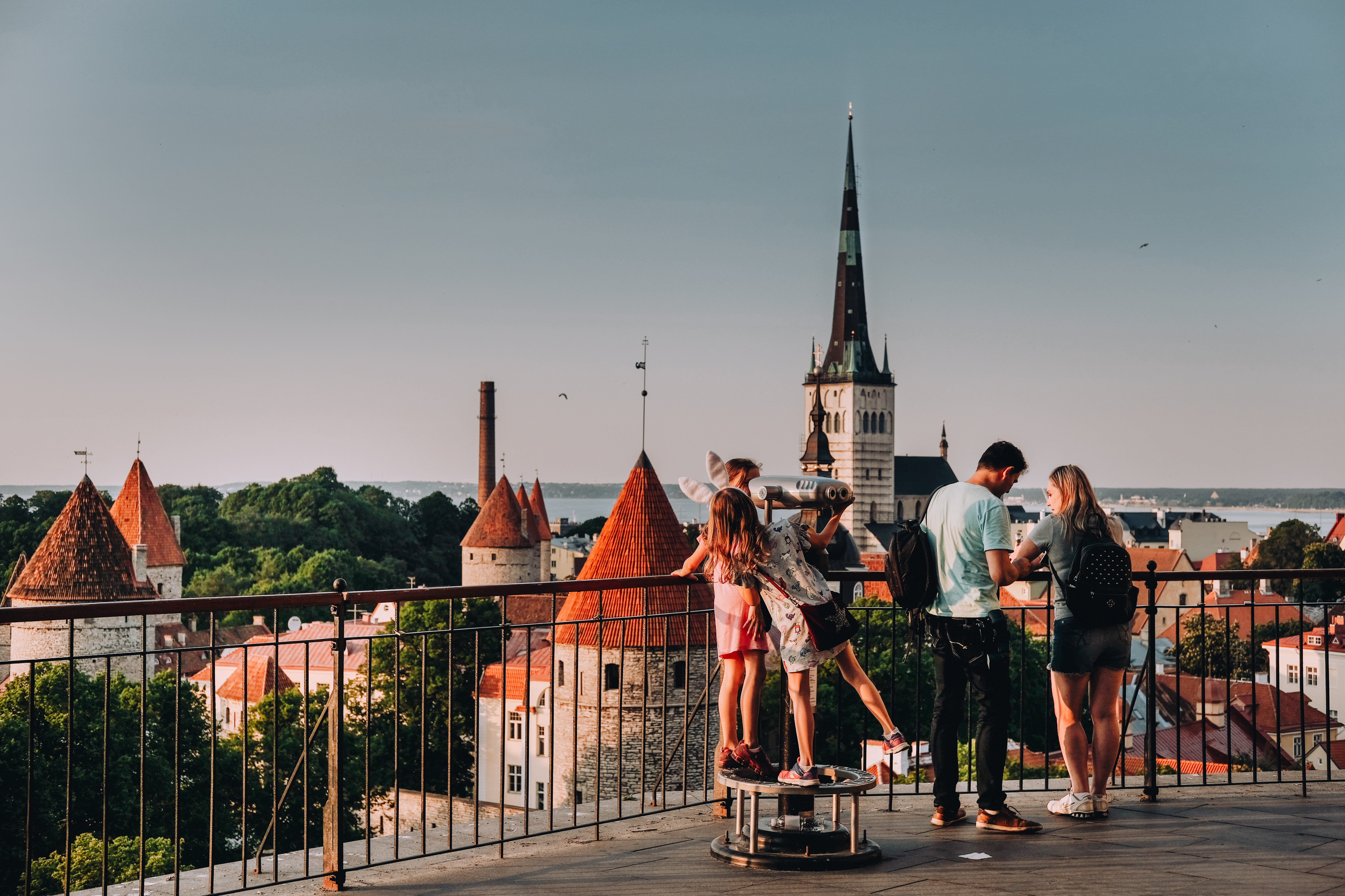 Люди на смотровой площадке Паткуль на Тоомпеа, Таллинн, летним вечером, на фоне башен городской стены и церкви Олевисте.