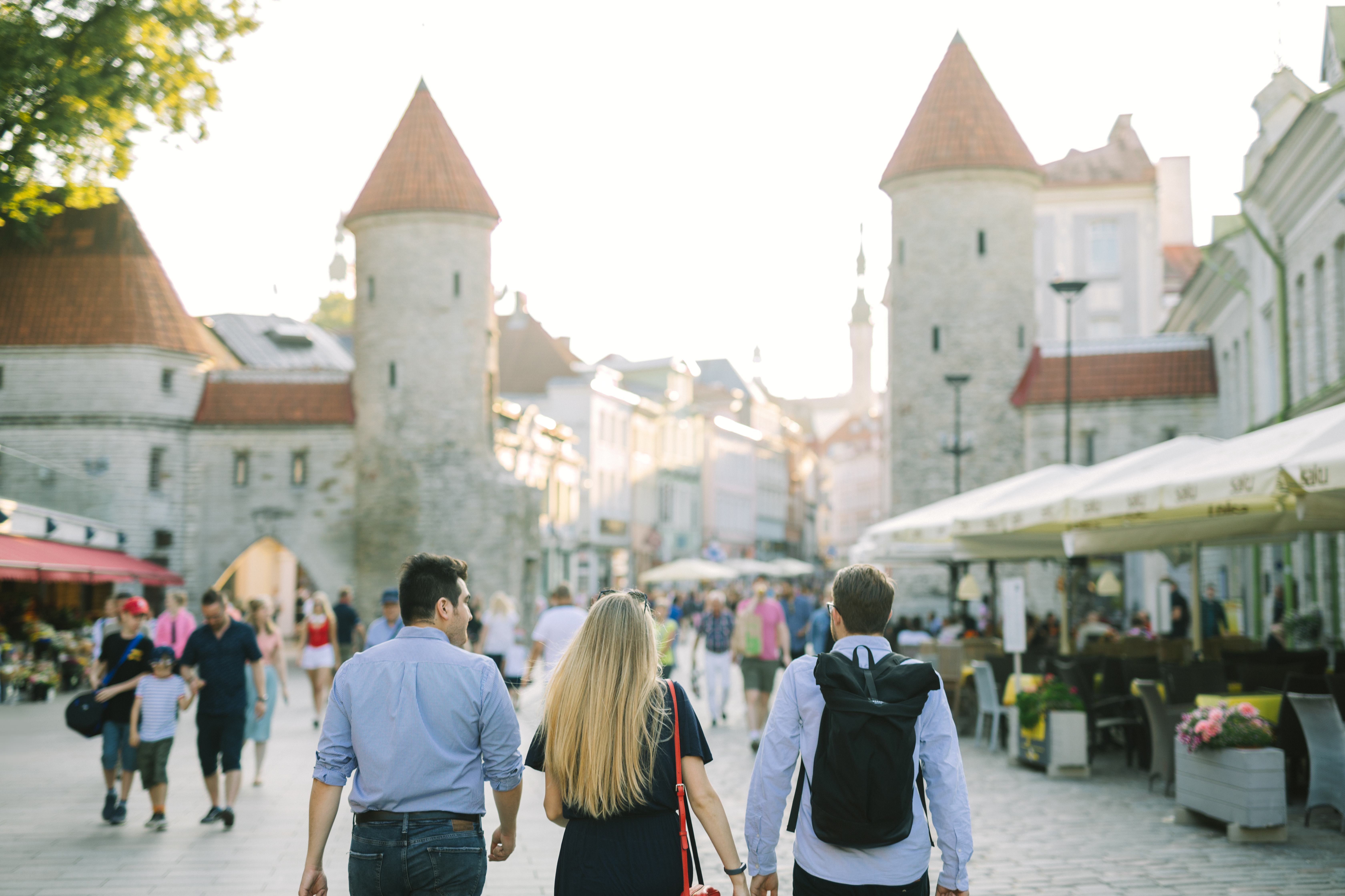 Kolm turisti jalutamas Tallinna vanalinnas Viru väravate poole.