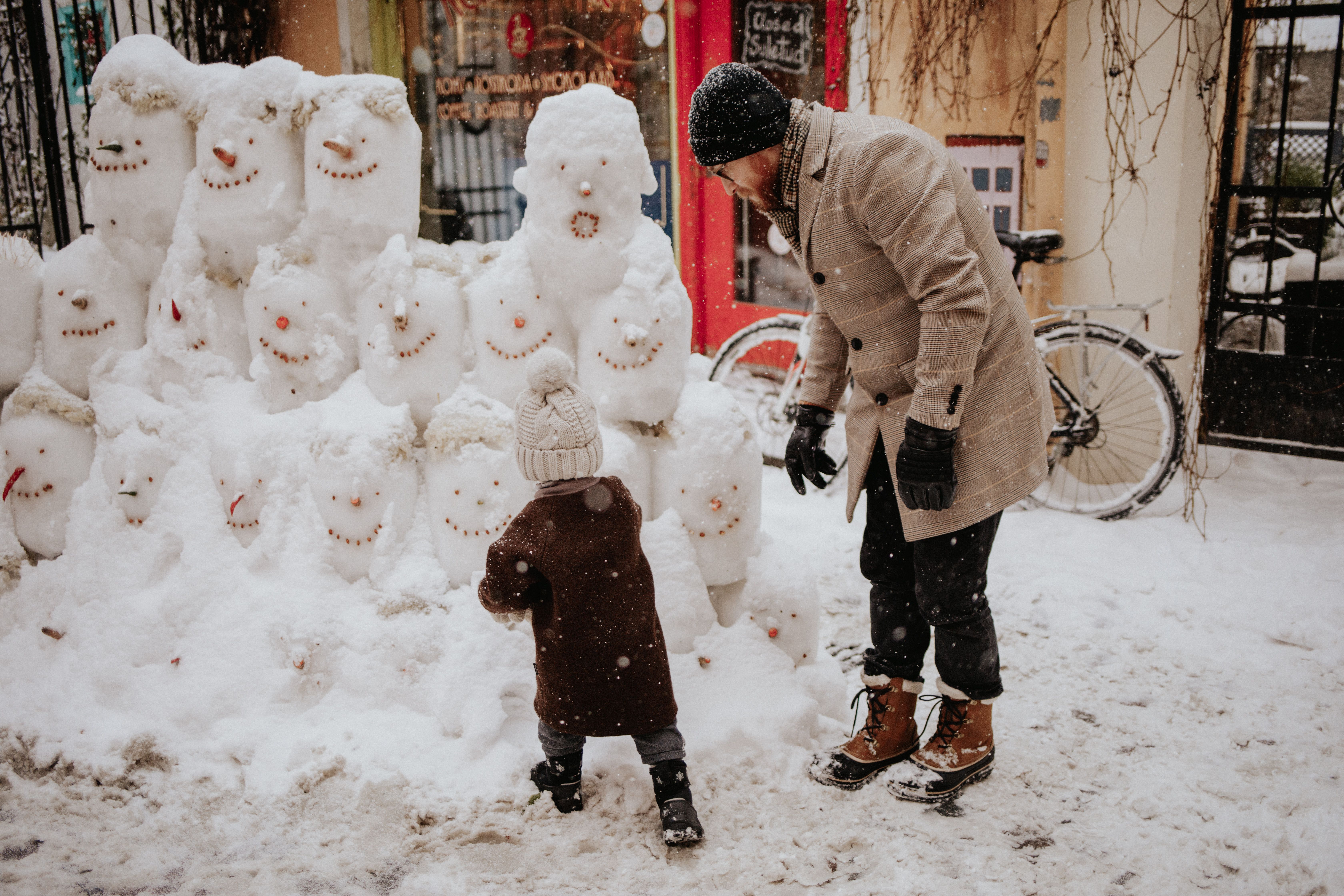 Little boy and his father playing with snowmen in the Old Town of Tallinn, Estonia.