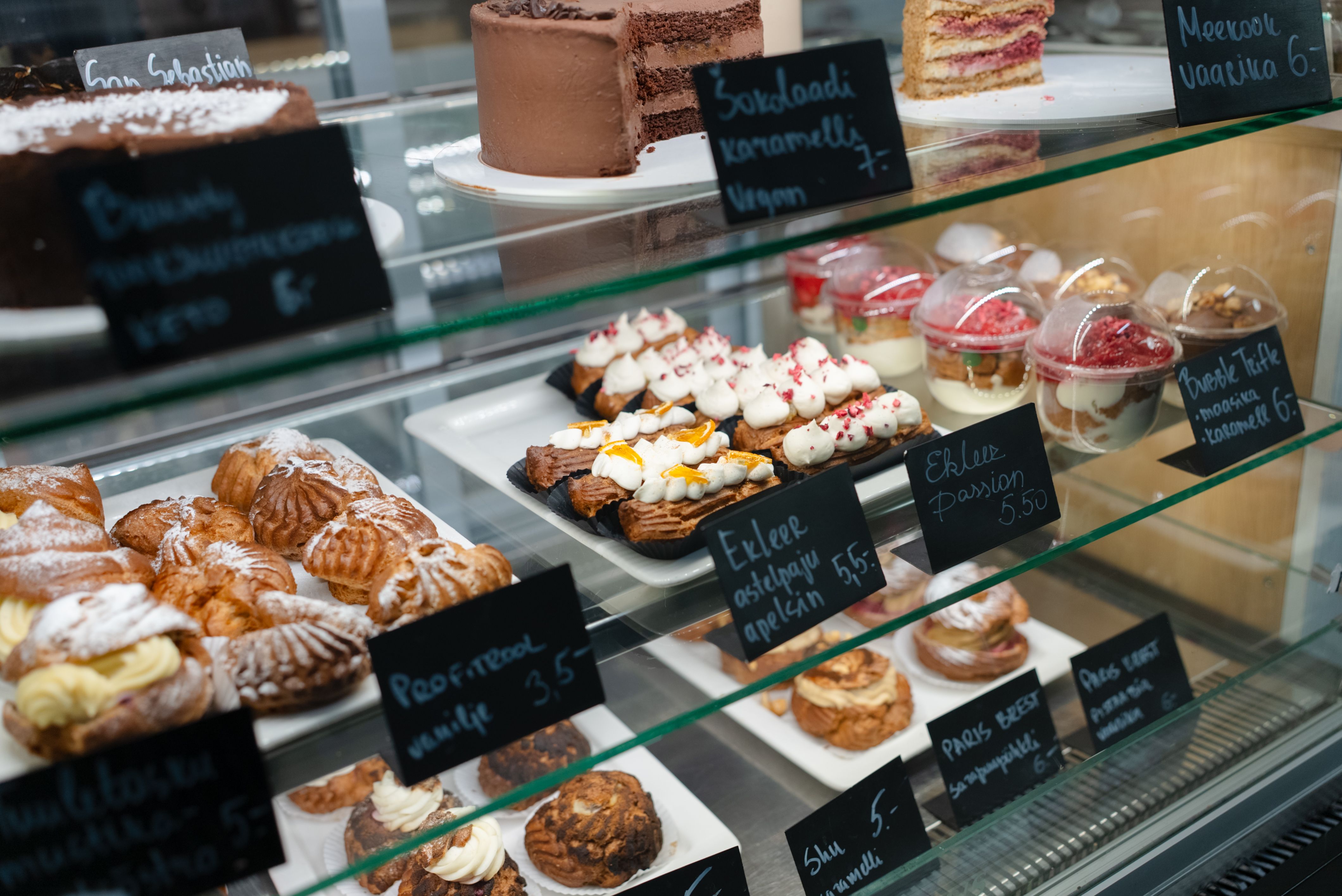 Käsintehdyt jälkiruoat Healthy Sweets By Polinassa Vitriini täynnä käsintehtyjä kakkuja ja laskiaispullia Healthy Sweets By Polina -kahvilassa.