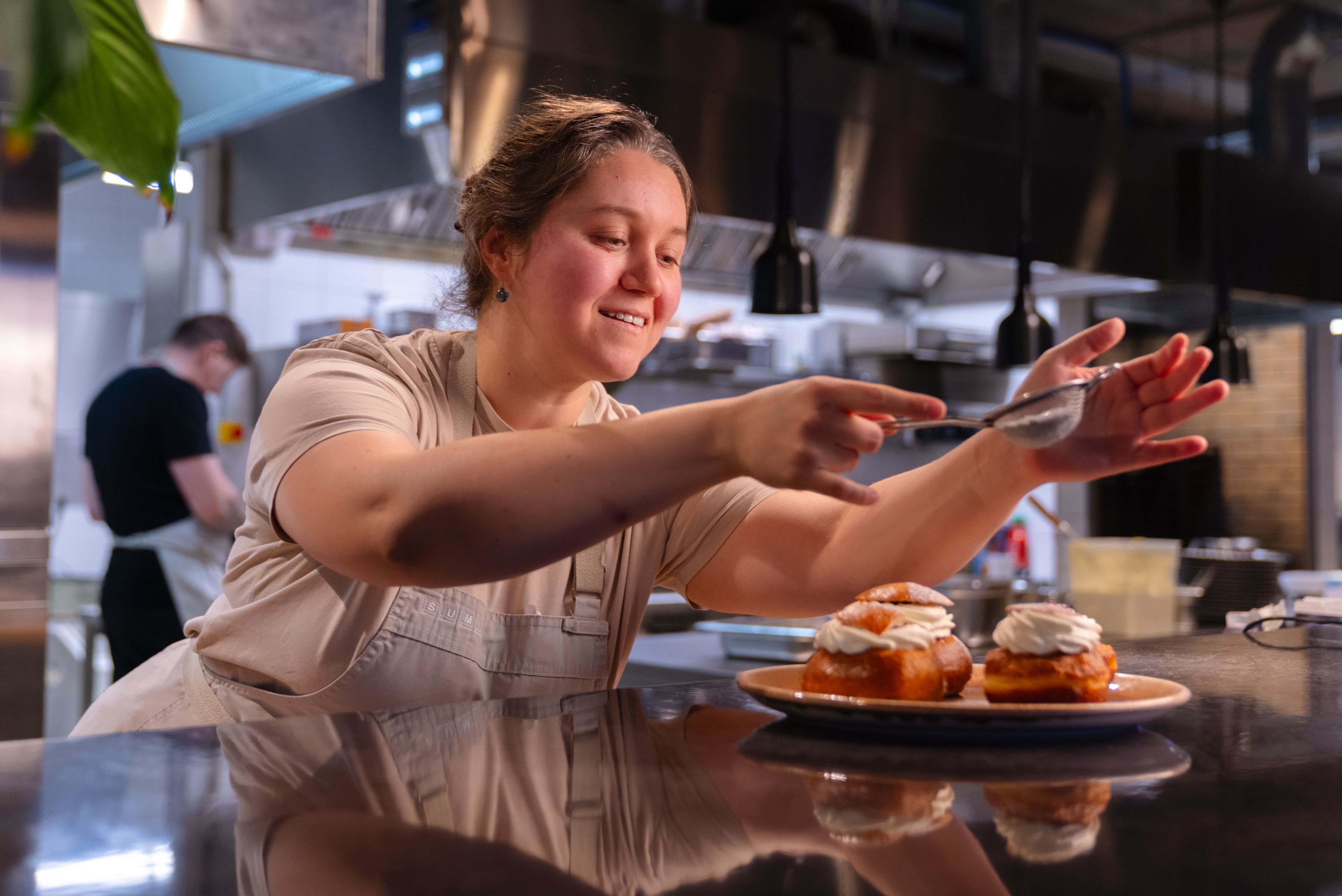Finishing cream buns in Sumi kitchen Baker Kristina decorating cream buns in the Sumi café kitchen ahead of Bun Fest.