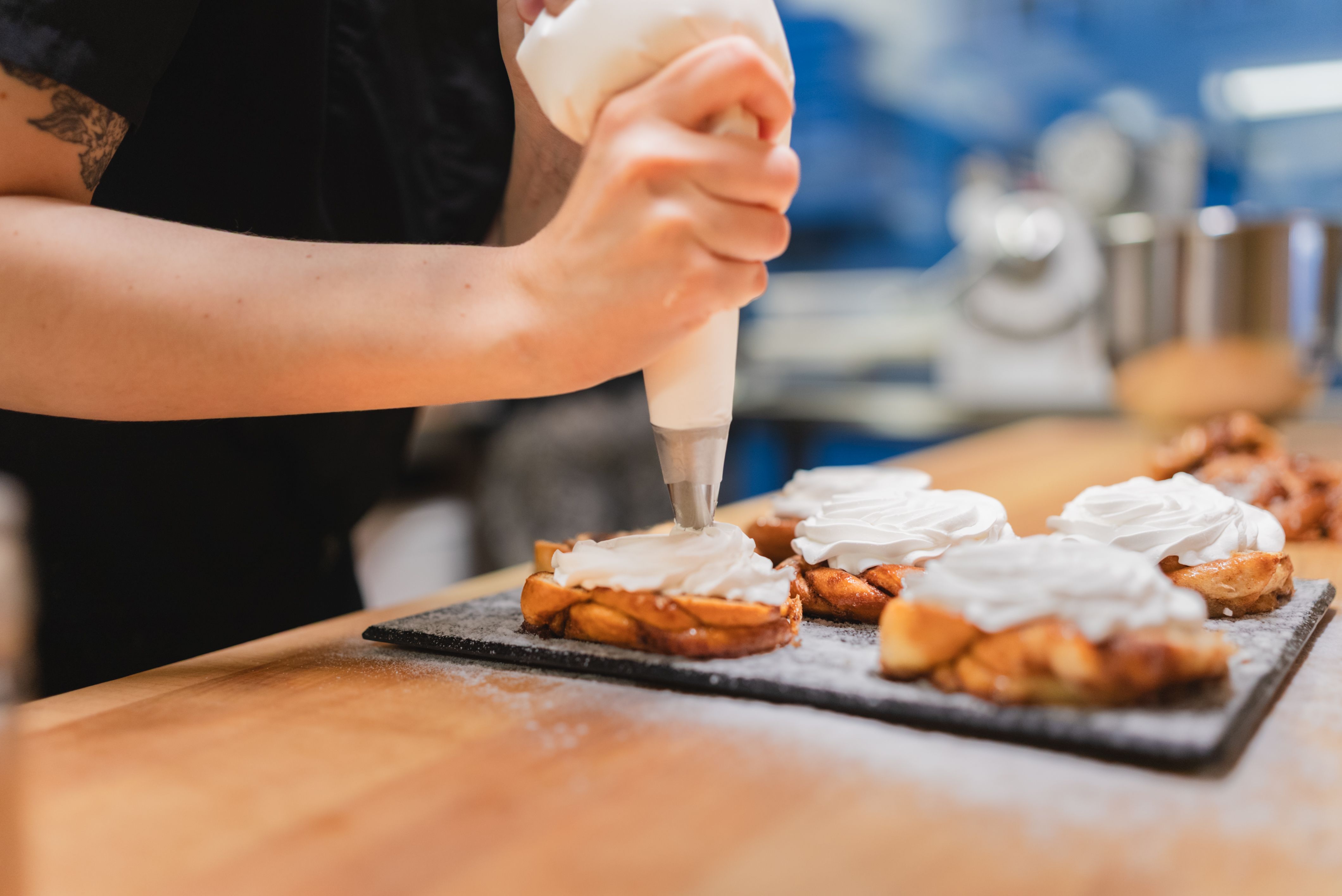 Laskiaispullien koristelu Kringelissä Kädet pursottavat kermavaahtoa laskiaispullien päälle Kringel-kahvilassa Tallinnassa, Tallinnan laskiaispullafestivaali 2026.