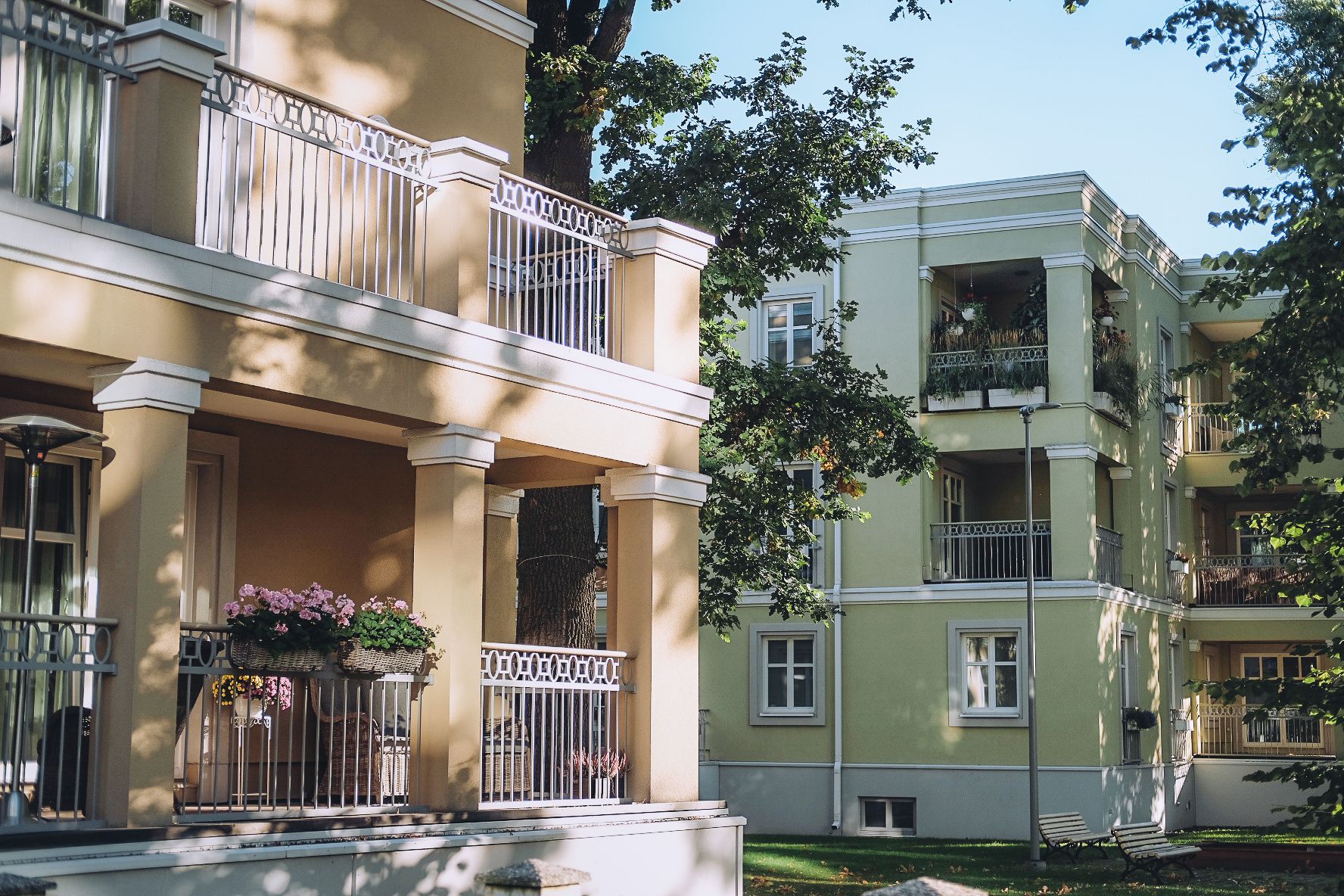 Close-up of pastel-colored apartment buildings with wrought iron balconies and flower boxes in the green and shady Kadriorg district on a summer day.
