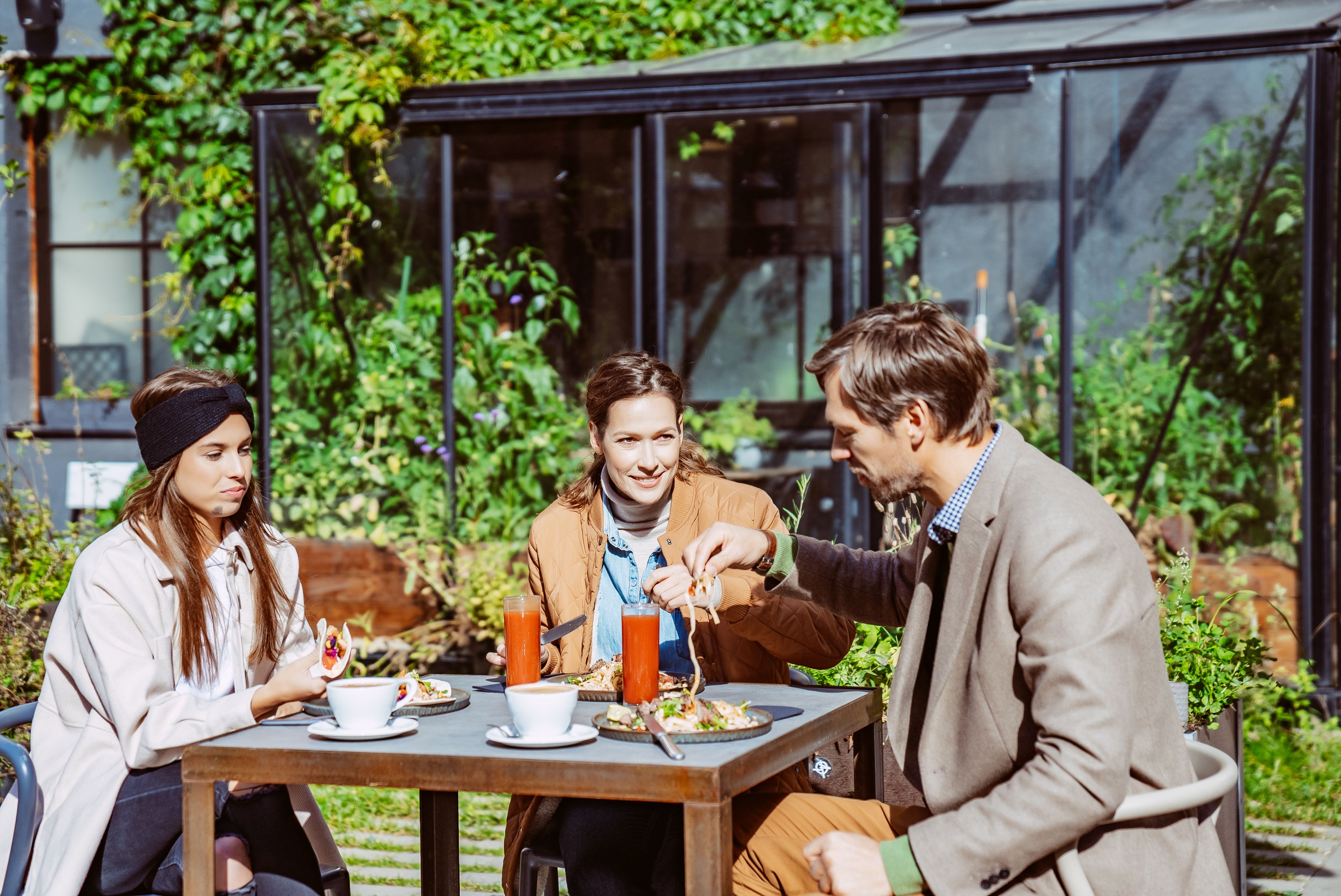 Two young women and a man eating outside at a restaurant in the Tartu Aparaaditehas area.