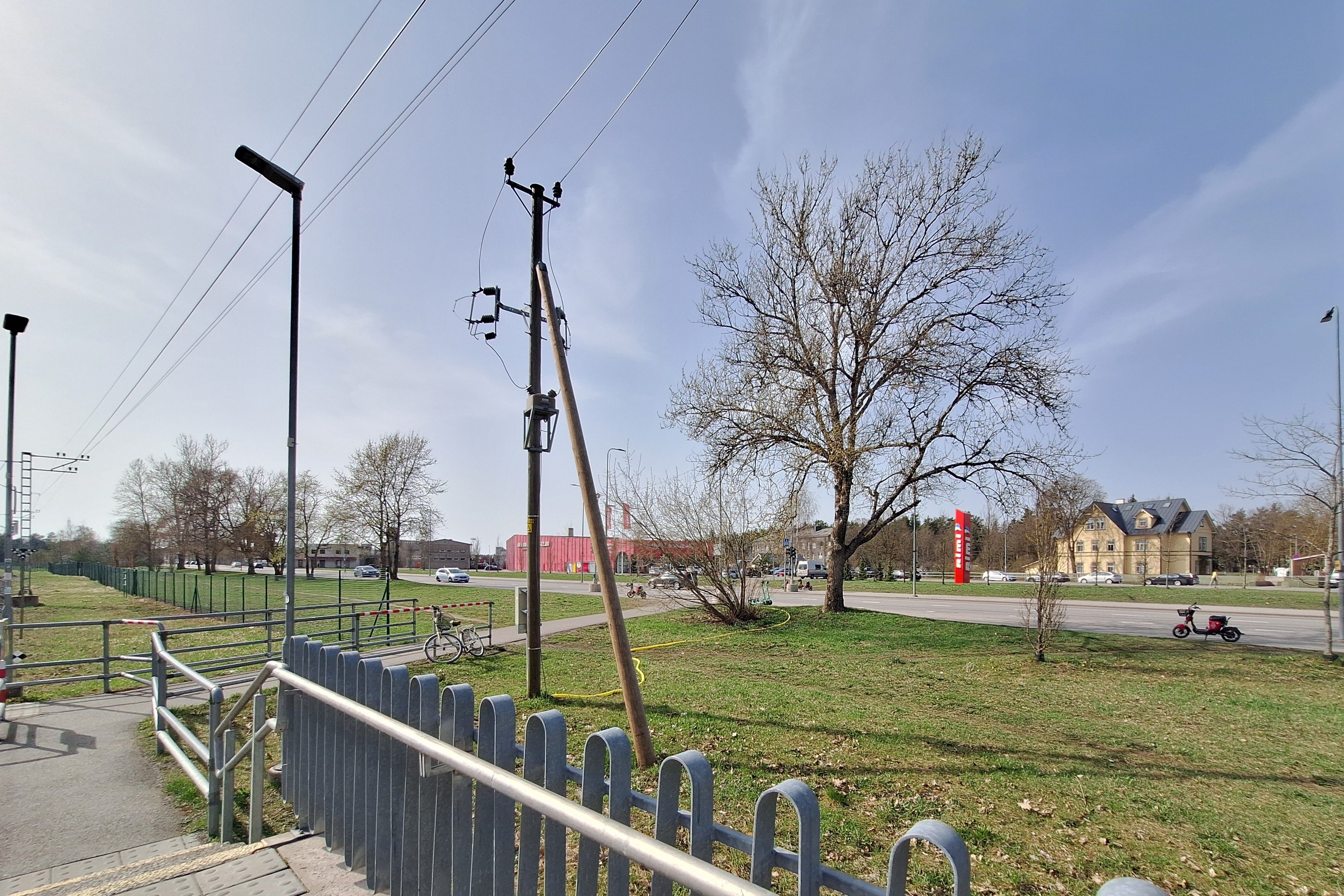Open green space with power lines and nearby roads, viewed from the Hiiu train stop area in Tallinn.