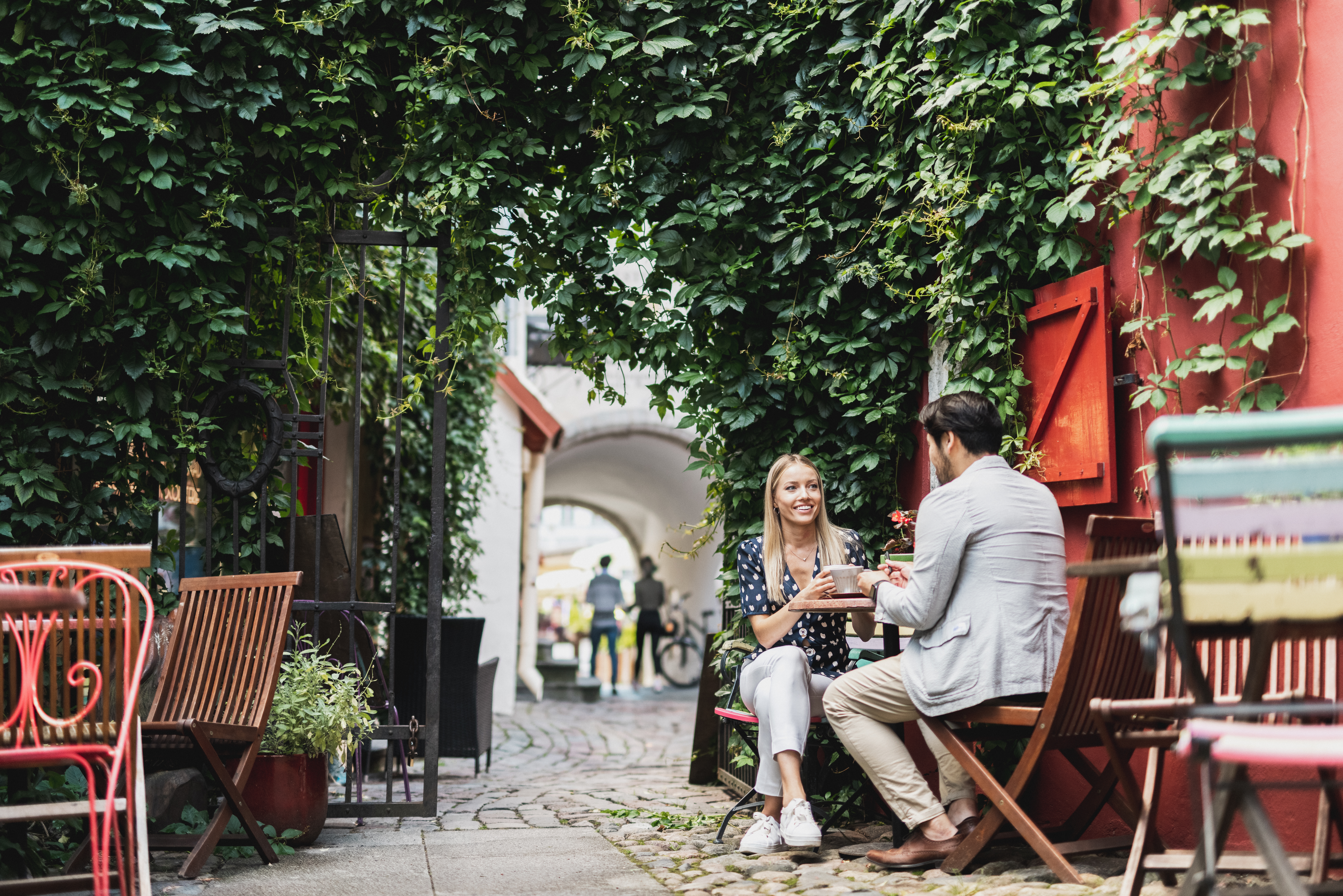 Молодая пара пьет кофе, сидя за столиком на летней террасе кафе в Старом городе летом, Старый город, Таллинн, Эстония